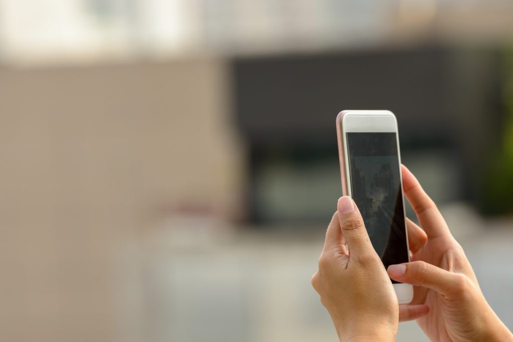 Woman hand photographing using mobile phone outdoors